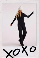 a lady in all black outfit with white beanie
